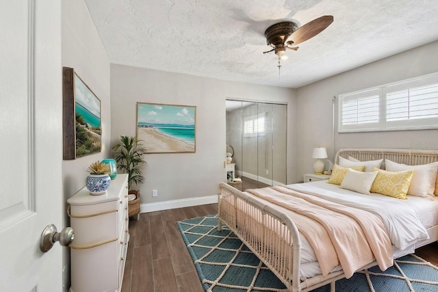 17 Bellevue Dr, Treasure Island, FL 33706 - bedroom with dark wood-style flooring, baseboards, a closet, a textured ceiling, and ceiling fan