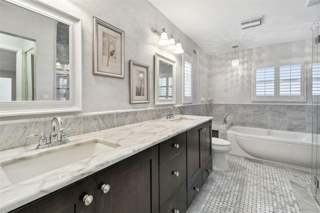 17 Bellevue Dr, Treasure Island, FL 33706 - full bathroom with tile walls, a garden tub, toilet, double vanity, and wainscoting