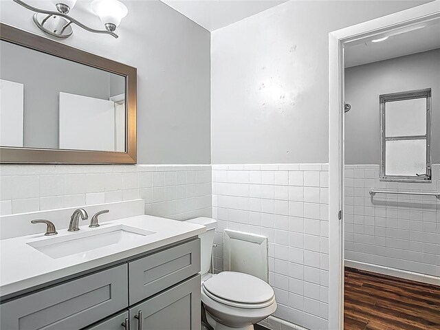 7280 Tarrytown Dr, Spring Hill, FL 34606 - bathroom featuring wood finished floors, wainscoting, tile walls, toilet, and vanity