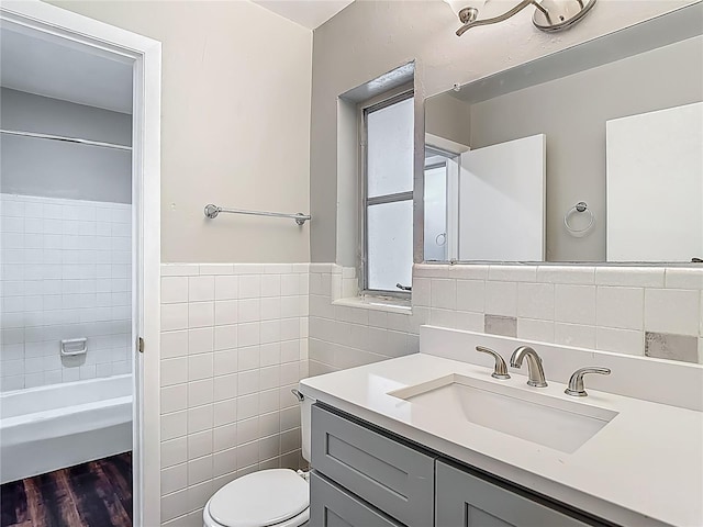 7280 Tarrytown Dr, Spring Hill, FL 34606 - bathroom with a wainscoted wall, toilet, tile walls, wood finished floors, and vanity