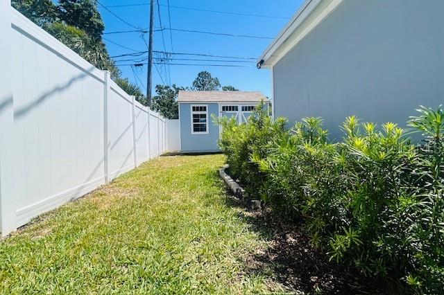 6401 30th Way N, Saint Petersburg, FL 33702 - view of yard featuring an outdoor structure, a storage unit, and a fenced backyard