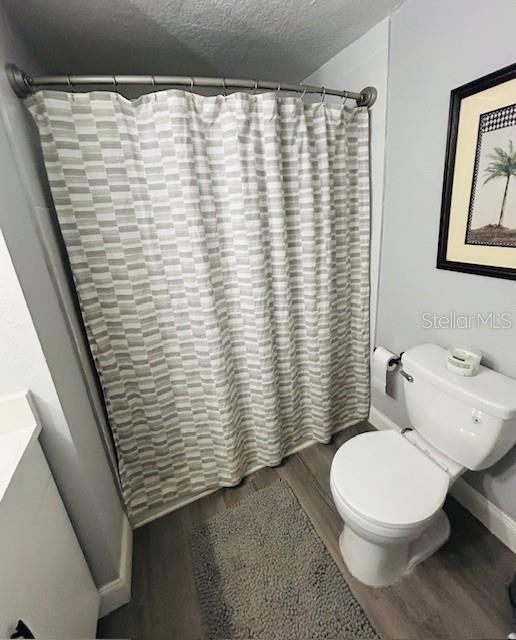 6401 30th Way N, Saint Petersburg, FL 33702 - full bathroom with wood finished floors, toilet, baseboards, and a shower with curtain