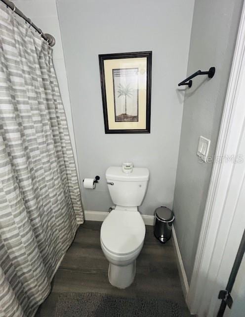 6401 30th Way N, Saint Petersburg, FL 33702 - bathroom featuring wood finished floors, toilet, baseboards, and a shower with curtain
