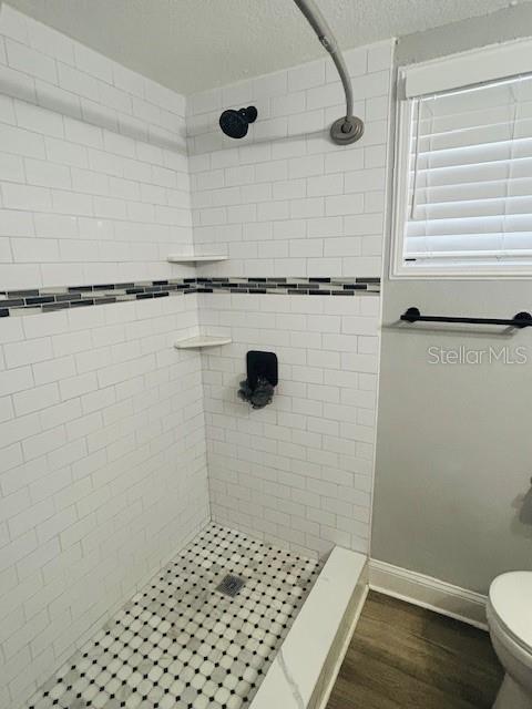 6401 30th Way N, Saint Petersburg, FL 33702 - bathroom featuring baseboards, toilet, wood finished floors, and tiled shower