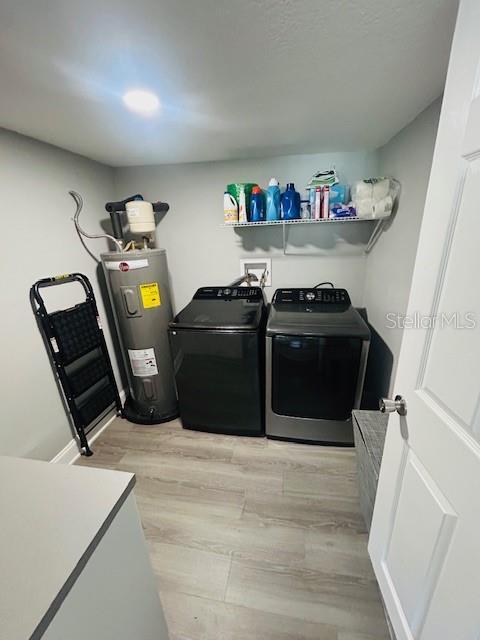 6401 30th Way N, Saint Petersburg, FL 33702 - laundry room featuring laundry area, light wood finished floors, washer and dryer, and electric water heater