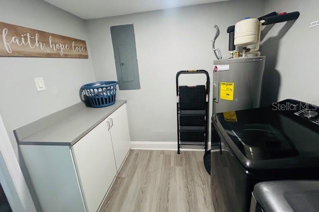 6401 30th Way N, Saint Petersburg, FL 33702 - laundry room with washing machine and clothes dryer, electric panel, light wood-style floors, water heater, and cabinet space
