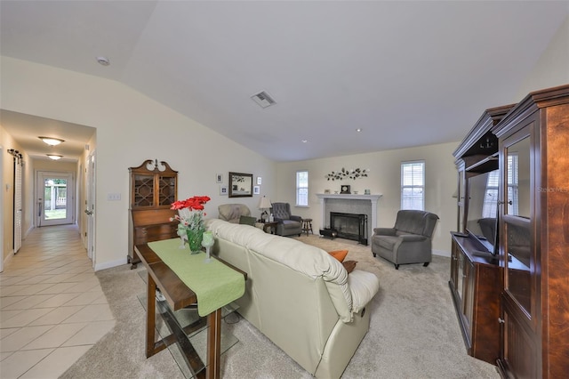 living room with vaulted ceiling, visible vents, a wealth of natural light, and a glass covered fireplace