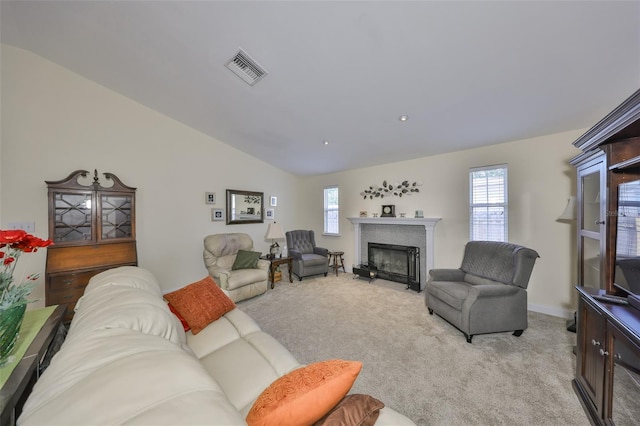 living area with visible vents, a fireplace with flush hearth, a wealth of natural light, and light carpet