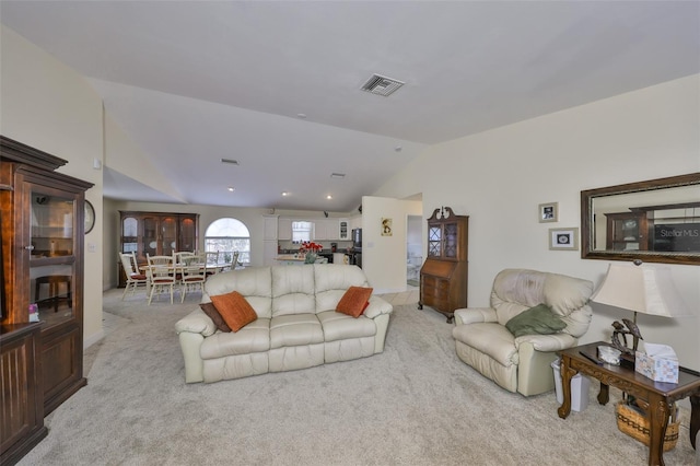 living area with lofted ceiling, visible vents, and carpet floors