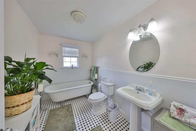 bathroom featuring toilet, a wainscoted wall, and a soaking tub