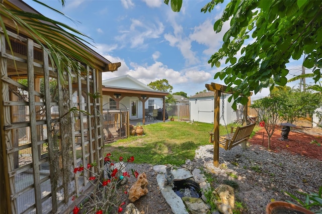 view of yard with an outdoor structure, a storage unit, a patio area, and fence