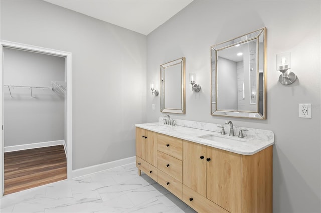 bathroom with a sink, baseboards, double vanity, and marble finish floor