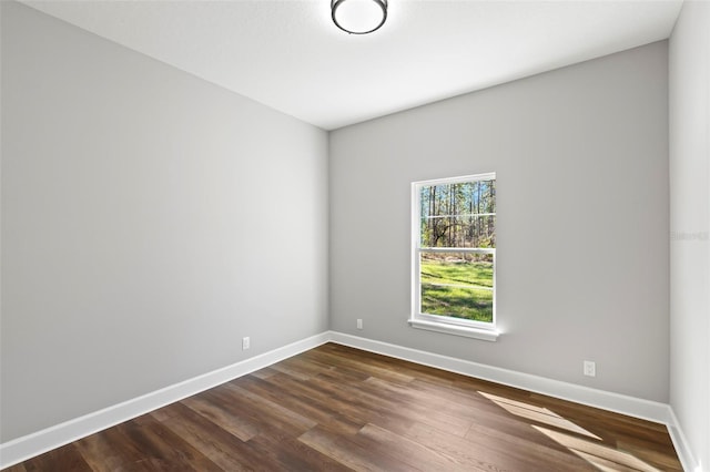 unfurnished room featuring baseboards and dark wood-style floors
