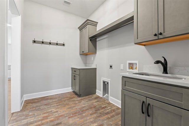 laundry room with a sink, brick floor, hookup for a washing machine, electric dryer hookup, and visible vents