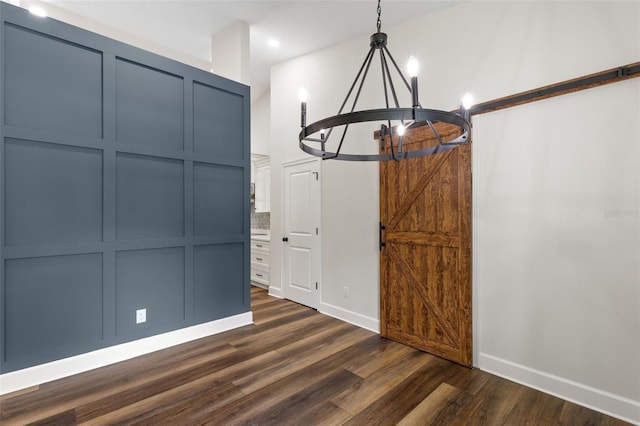 unfurnished dining area with a notable chandelier, a barn door, recessed lighting, baseboards, and dark wood-type flooring