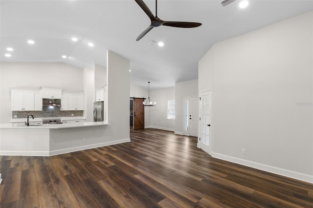 unfurnished living room with baseboards, ceiling fan, dark wood-style floors, high vaulted ceiling, and a barn door