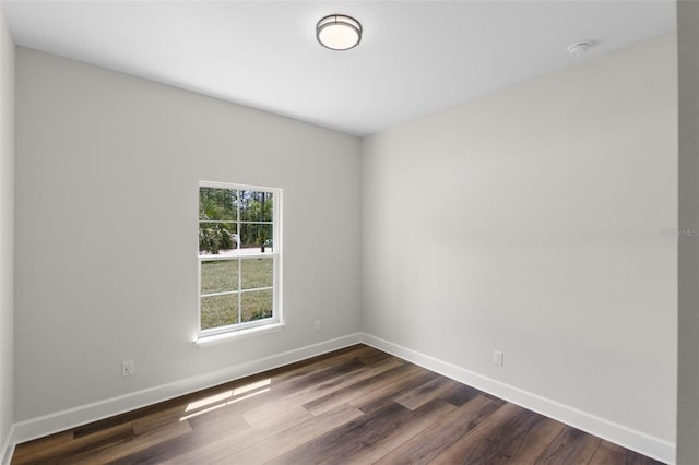 empty room featuring baseboards and dark wood-type flooring