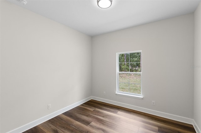 spare room with baseboards and dark wood finished floors