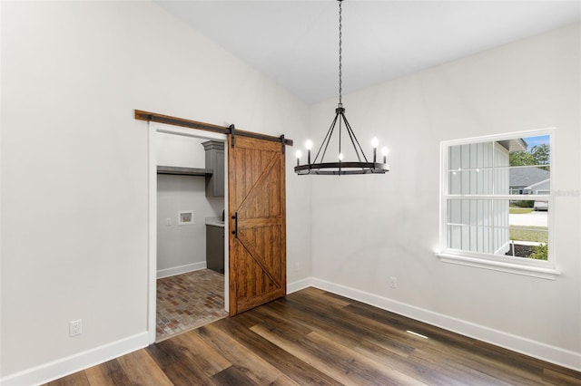unfurnished dining area featuring baseboards, a chandelier, a barn door, and dark wood-type flooring
