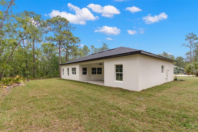 rear view of property featuring a patio, ceiling fan, a lawn, and stucco siding