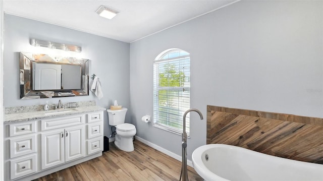 4396 5th Isle Dr, Hernando Beach, FL 34607 - full bathroom with vanity, wood finished floors, toilet, baseboards, and a freestanding bath