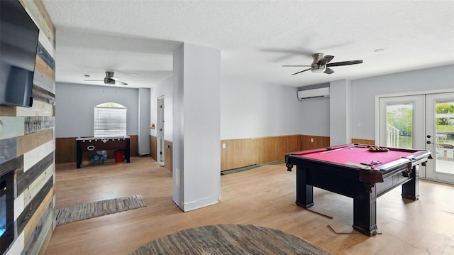 4396 5th Isle Dr, Hernando Beach, FL 34607 - game room featuring wainscoting, a wall mounted air conditioner, a fireplace, a ceiling fan, and a wealth of natural light