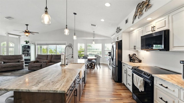 4396 5th Isle Dr, Hernando Beach, FL 34607 - kitchen with visible vents, freestanding refrigerator, wood finished floors, black / electric stove, and vaulted ceiling