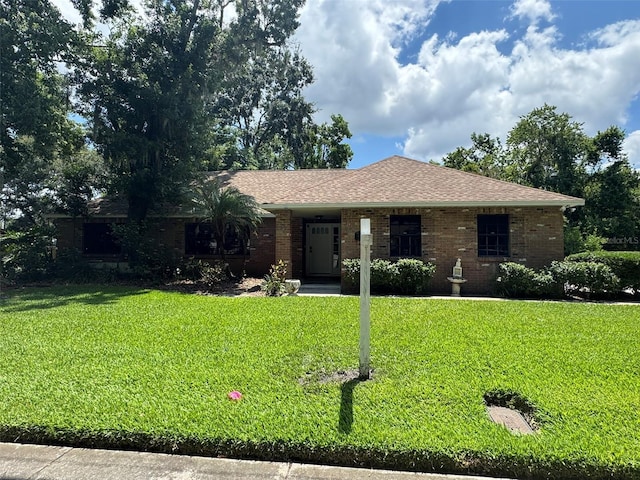 ranch-style house featuring a front lawn, brick siding, and roof with shingles
