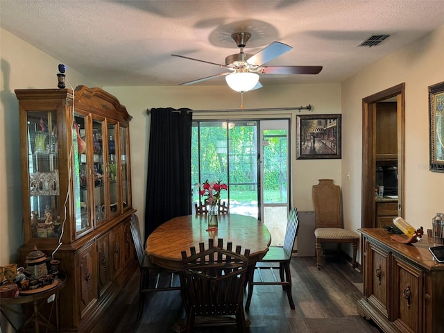 dining space featuring dark wood-style flooring, ceiling fan, and a textured ceiling