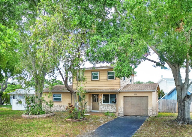 771 Murphy Ave N, Saint Petersburg, FL 33703 - view of front of house with stone siding, an attached garage, driveway, a porch, and stucco siding