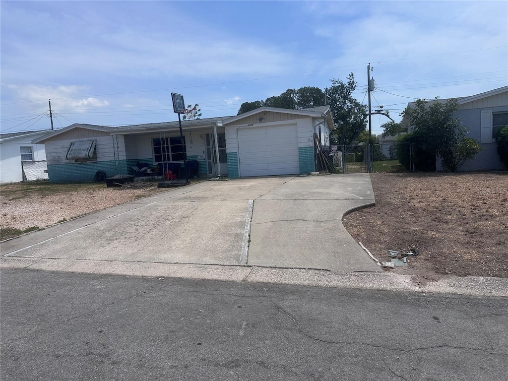 4920 Zodiac Ave, Holiday, FL 34690 - ranch-style home with fence, an attached garage, concrete driveway, and brick siding