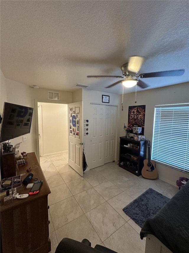 foyer entrance with visible vents, light tile patterned floors, ceiling fan, and a textured ceiling
