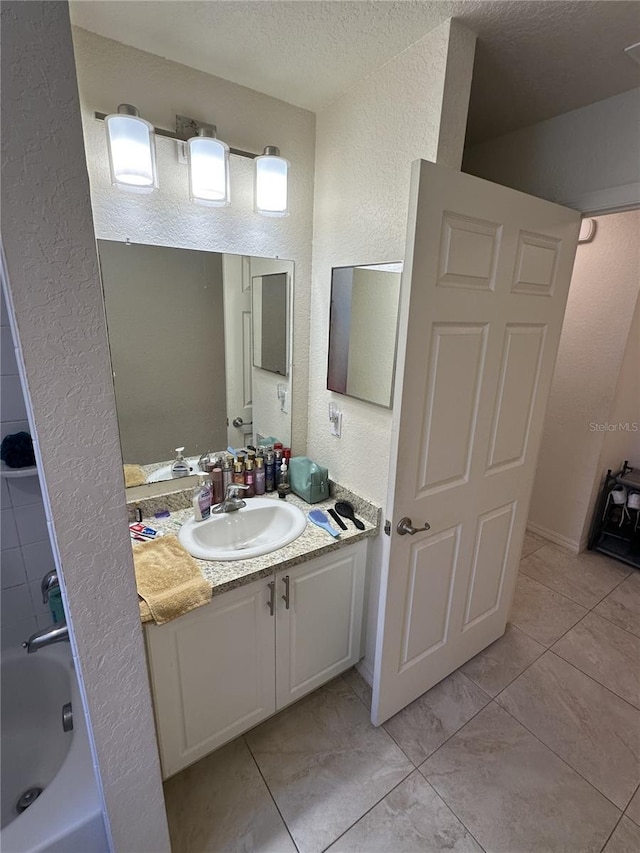 full bathroom featuring a textured ceiling, a textured wall, and vanity