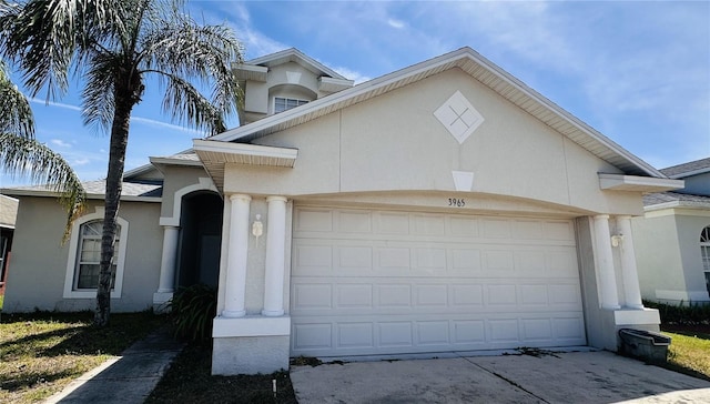 view of front facade featuring concrete driveway, stucco siding, and an attached garage