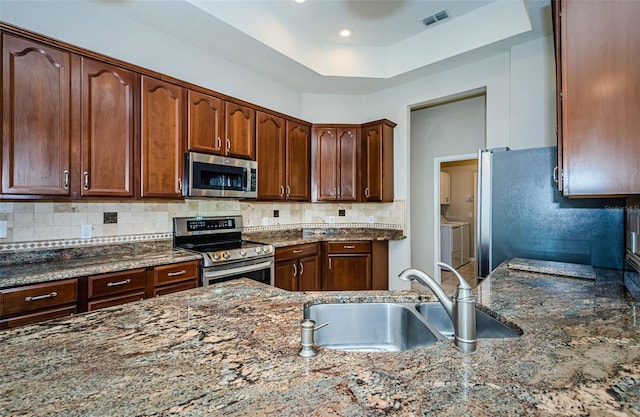 617 Glastonbury Ct, Spring Hill, FL 34609 - kitchen with stainless steel appliances, a sink, dark stone counters, decorative backsplash, and a raised ceiling