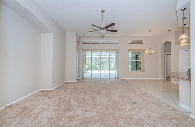 617 Glastonbury Ct, Spring Hill, FL 34609 - unfurnished living room featuring ceiling fan, arched walkways, baseboards, light colored carpet, and light tile patterned floors