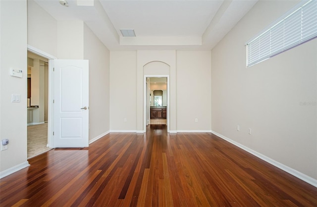 617 Glastonbury Ct, Spring Hill, FL 34609 - empty room with wood finished floors, a tray ceiling, arched walkways, and baseboards