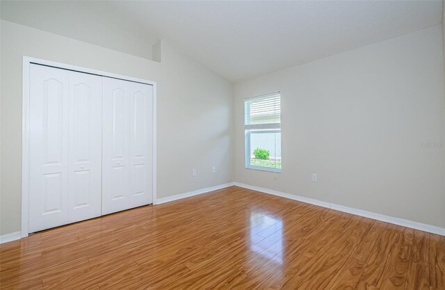 617 Glastonbury Ct, Spring Hill, FL 34609 - unfurnished bedroom with light wood-type flooring, lofted ceiling, baseboards, and a closet