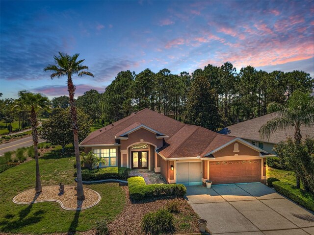 617 Glastonbury Ct, Spring Hill, FL 34609 - view of front of house with french doors, stucco siding, an attached garage, and a lawn