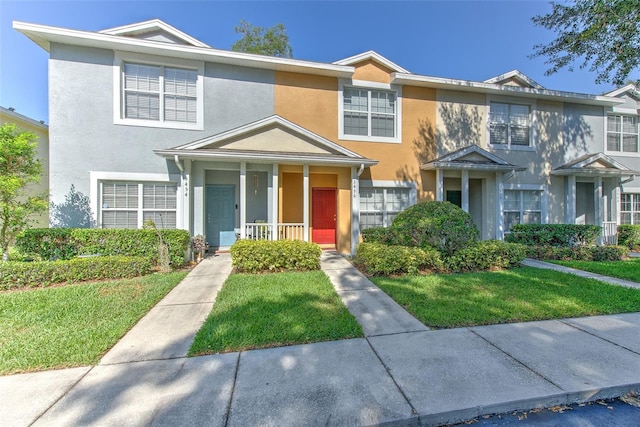 3456 High Hampton Cir, Tampa, FL 33610 - townhome / multi-family property featuring a porch, a front yard, and stucco siding
