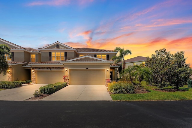 view of front of home featuring a garage, stone siding, stucco siding, concrete driveway, and a tile roof