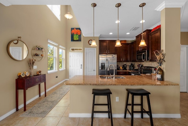 kitchen with visible vents, a peninsula, light stone counters, a sink, and appliances with stainless steel finishes