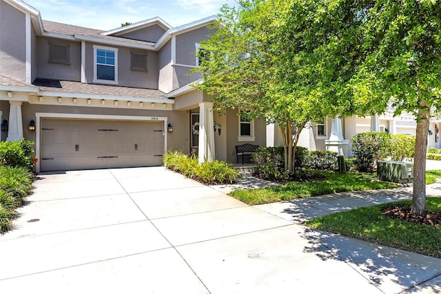 view of front of property with an attached garage, roof with shingles, stucco siding, and driveway