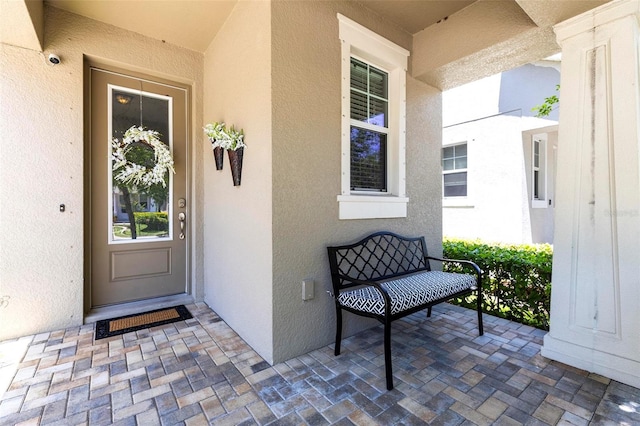 property entrance featuring stucco siding and covered porch