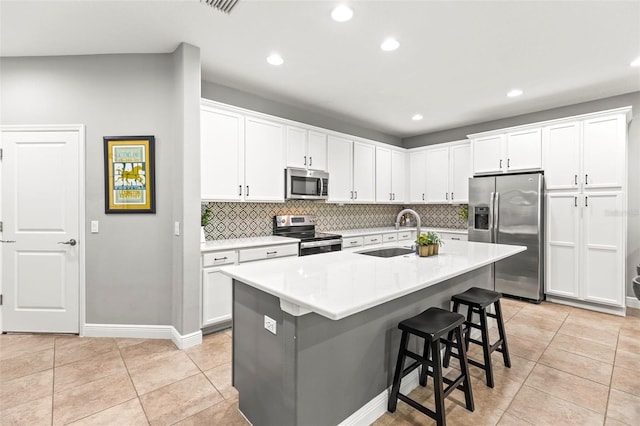 kitchen with decorative backsplash, appliances with stainless steel finishes, a sink, recessed lighting, and white cabinetry