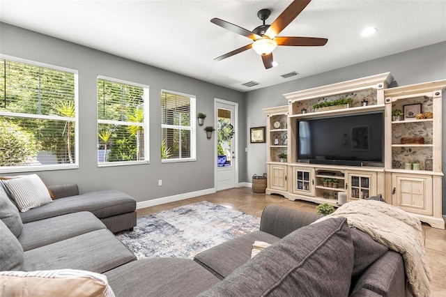 living area featuring baseboards, ceiling fan, and visible vents