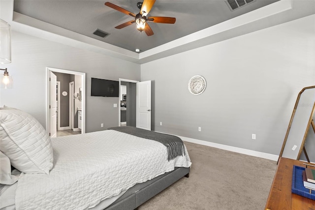 carpeted bedroom featuring a raised ceiling, baseboards, connected bathroom, and visible vents