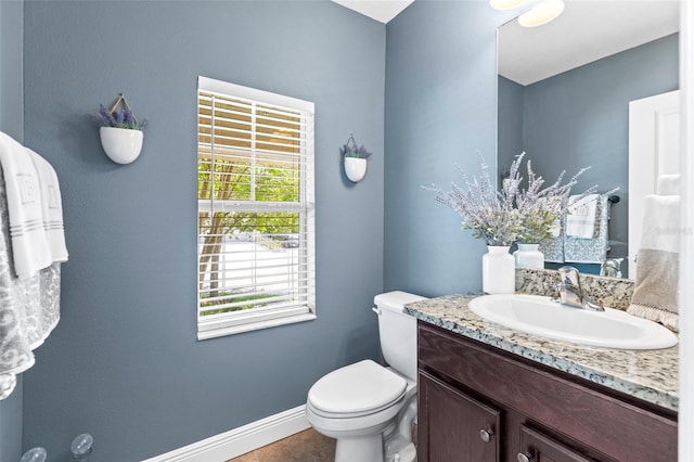 bathroom with baseboards, vanity, and toilet