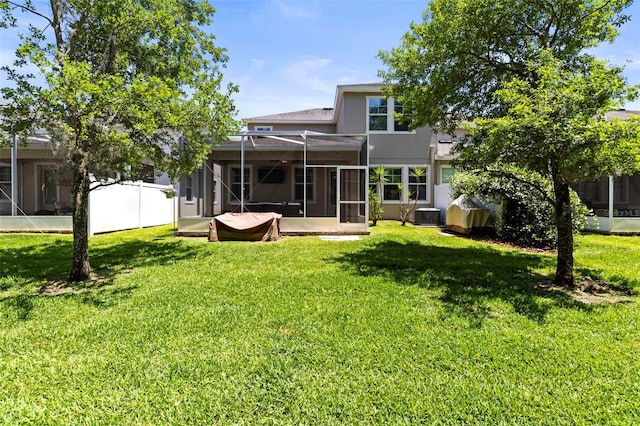 rear view of property with a sunroom, a lawn, and central AC