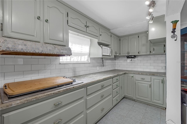 2014 E Broad St, Tampa, FL 33610 - kitchen with white microwave, backsplash, stovetop, and light tile patterned flooring